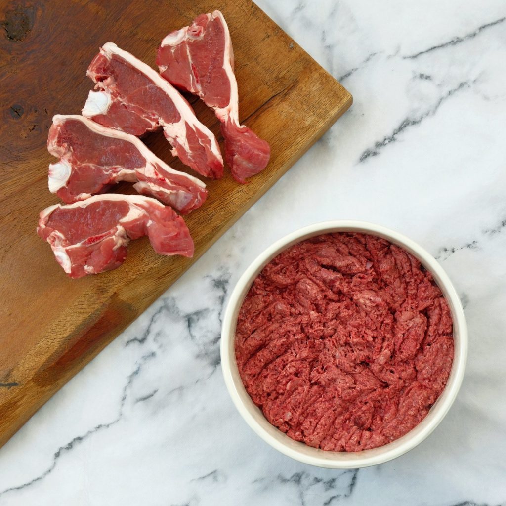 Lamb mince in a dog bowl with lamb chops on a chopping board
