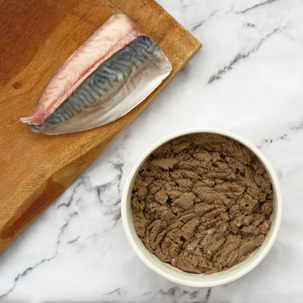 Oily fish mince in a dog bowl with fillets of mackerel on a chopping board